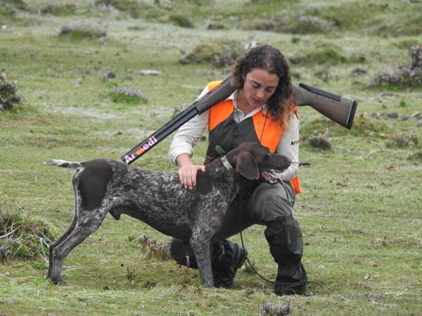 Cazadora con su perro de caza en el campo en trofeo caza y conservación